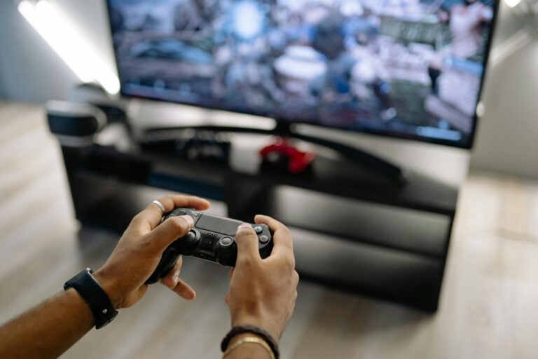 Close-up of hands holding a gaming controller while playing video games indoors.